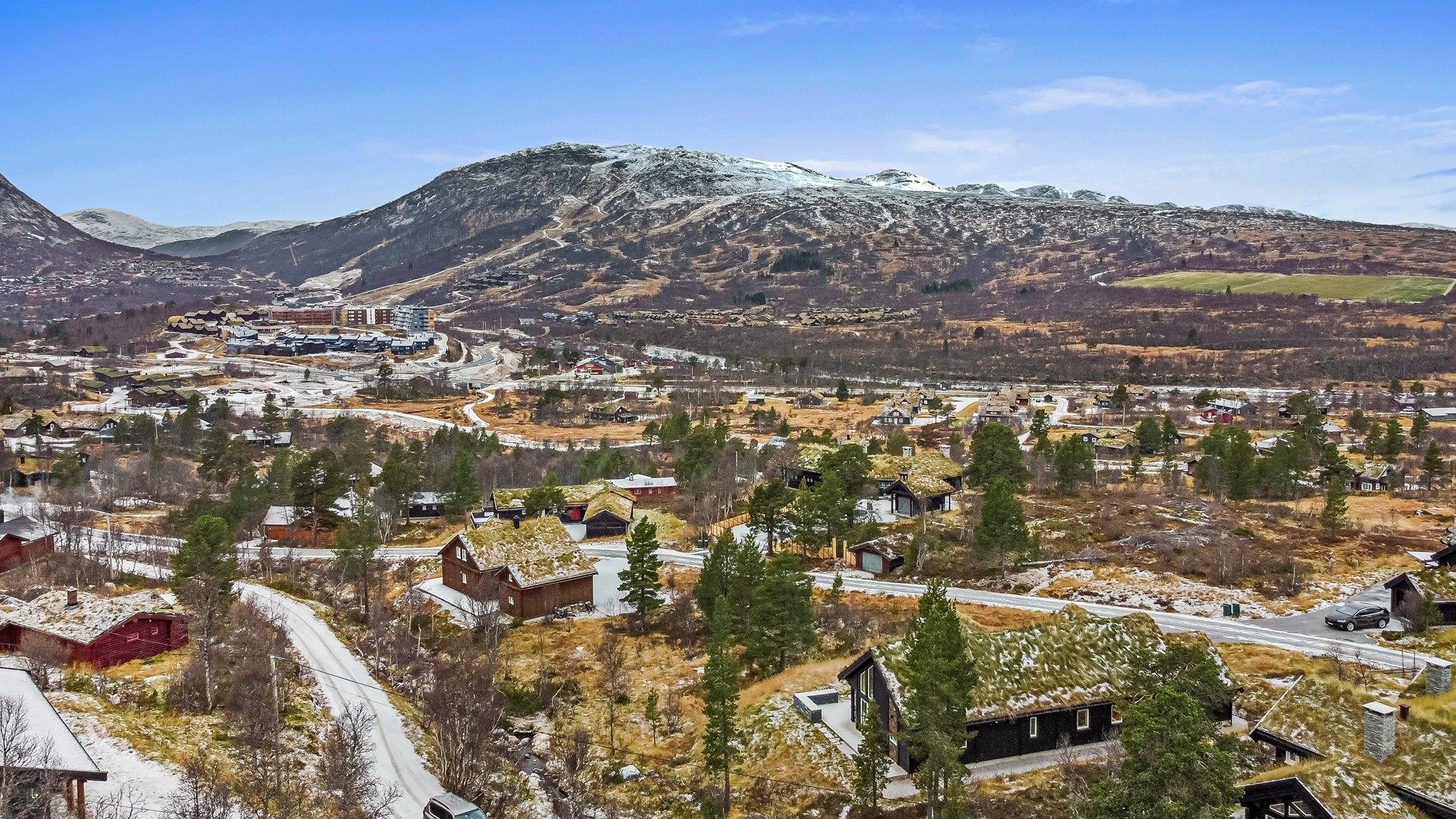 Beliggenhet med skisenteret i bakgrunnen og skiløypa midt i bildet.