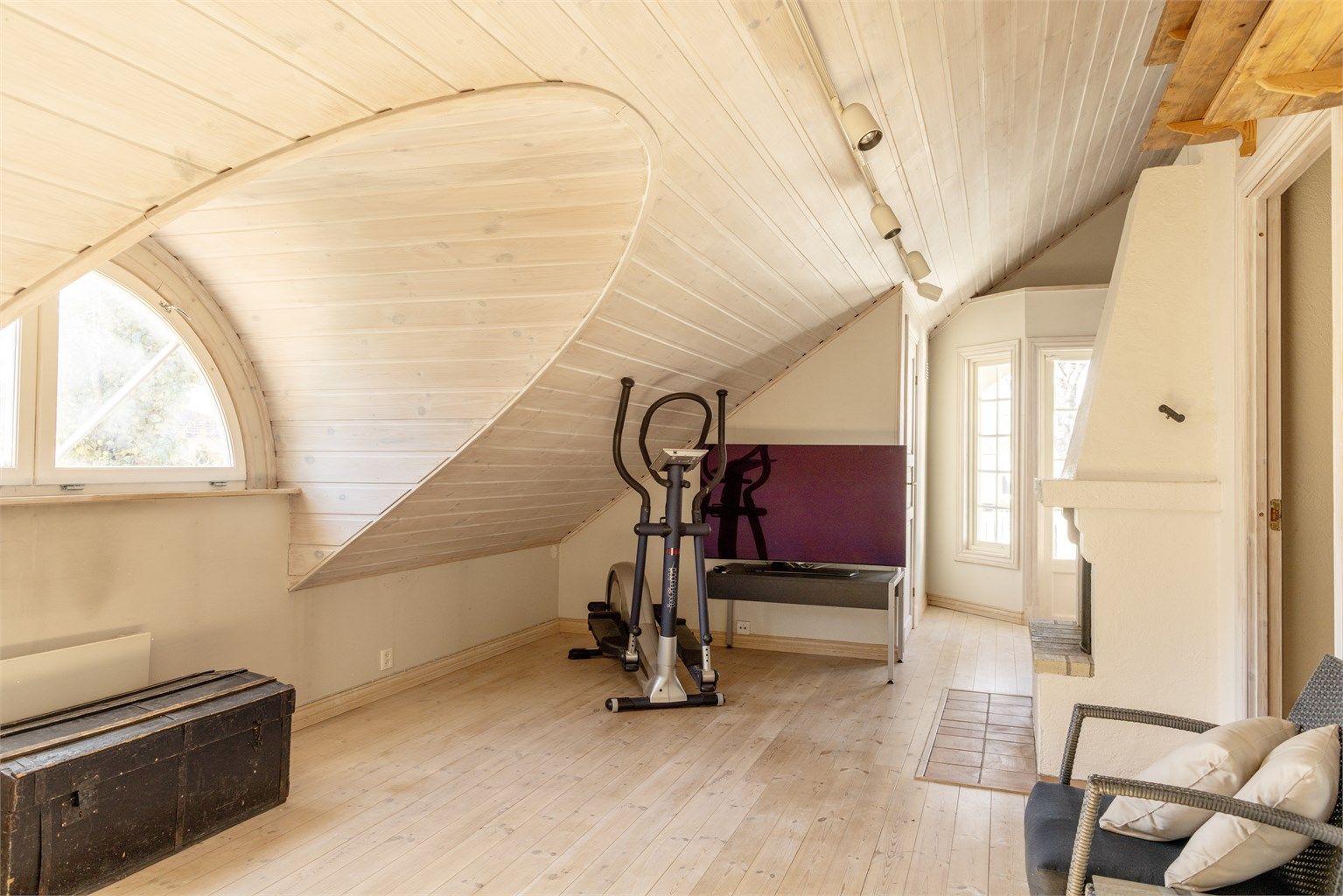 Romslig loftstue med stor gulvflate, høy himling og ark med det karakteristiske, halvrunde vinduet.