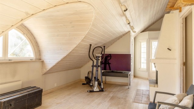 Romslig loftstue med stor gulvflate, høy himling og ark med det karakteristiske, halvrunde vinduet.