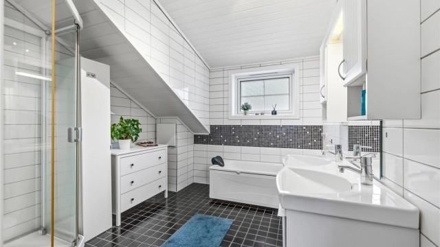 Badet i loftsetasjen byr på både et frittstående badekar og et separat dusjkabinett.