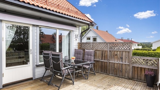 Terrassen har rekkverk i tre og levegg mot nabo.