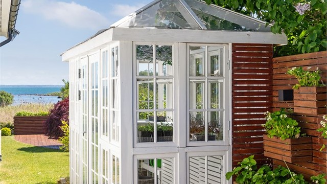 Sjarmerende, hvitmalt drivhus med sprossevinduer og glasstak - flere plassbygde plantekasser, godt tilrettelagt for hobbygartneren.