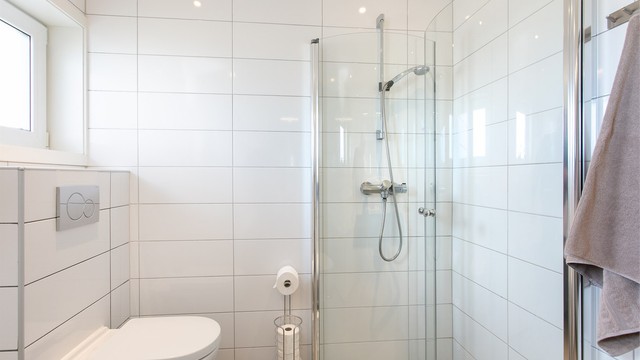 Dusjhjørne med foldbare glassvegger og vegghengt dusjarmatur. Vegghengt toalett. Elektrisk styrt vifte