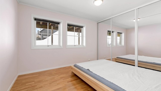 Hovedsoverom i utleieleiligheten er utstyrt med en stor skyvedørsgarderobe som gir rikelig med lagringsplass.