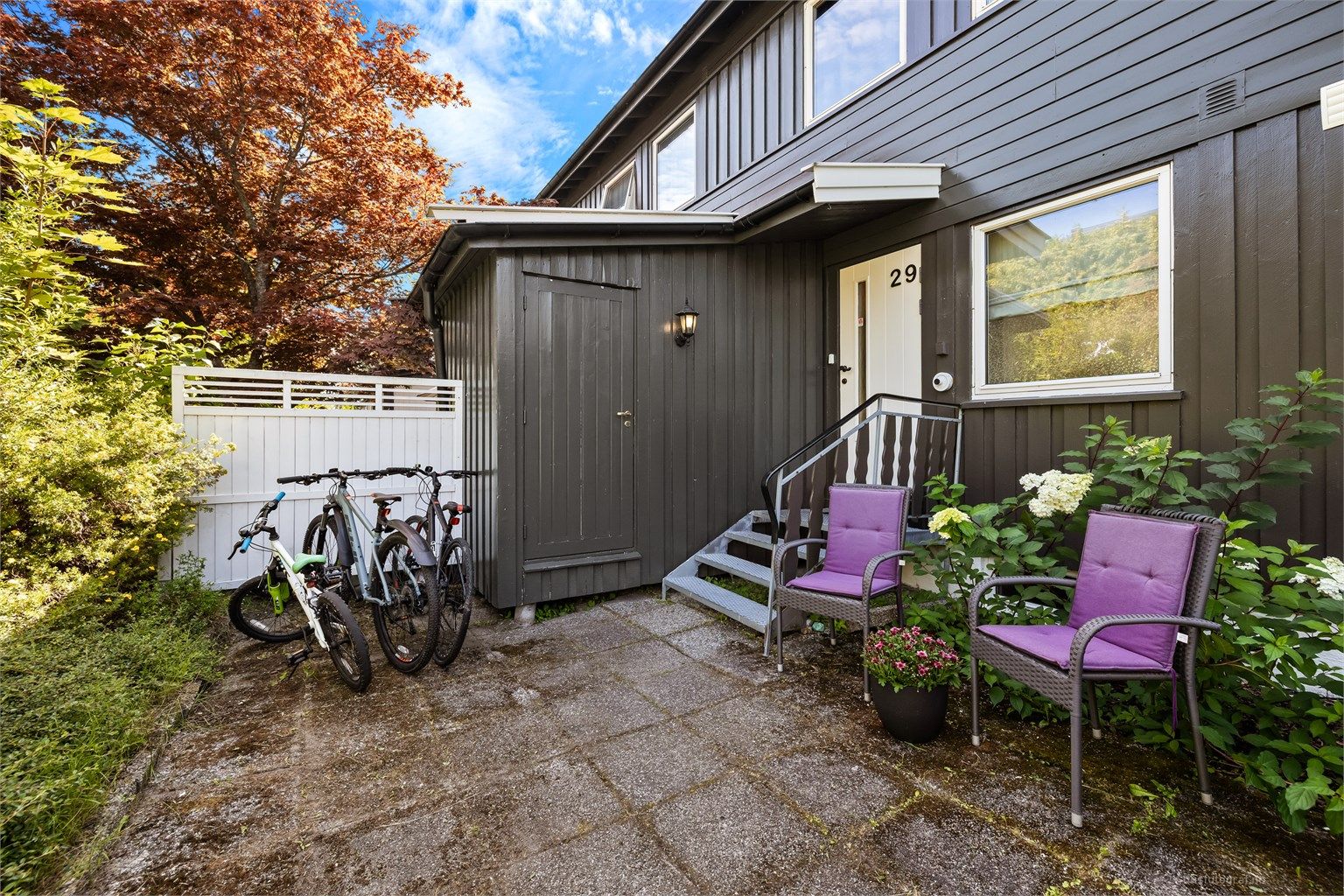 Hellelagt uteområde ved inngangen med plass til liten sittegruppe og sykkelparkering. Trapp opp til overbygd inngangsparti.