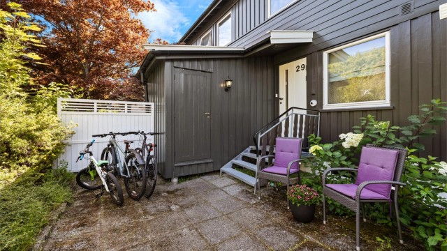 Hellelagt uteområde ved inngangen med plass til liten sittegruppe og sykkelparkering. Trapp opp til overbygd inngangsparti.