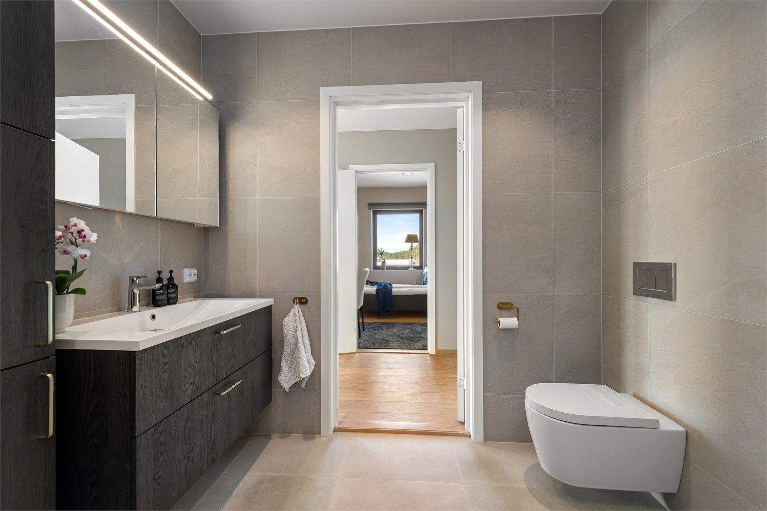 Badet har vegghengt toalett og et romslig dusjhjørne med både regn- og hånddusj