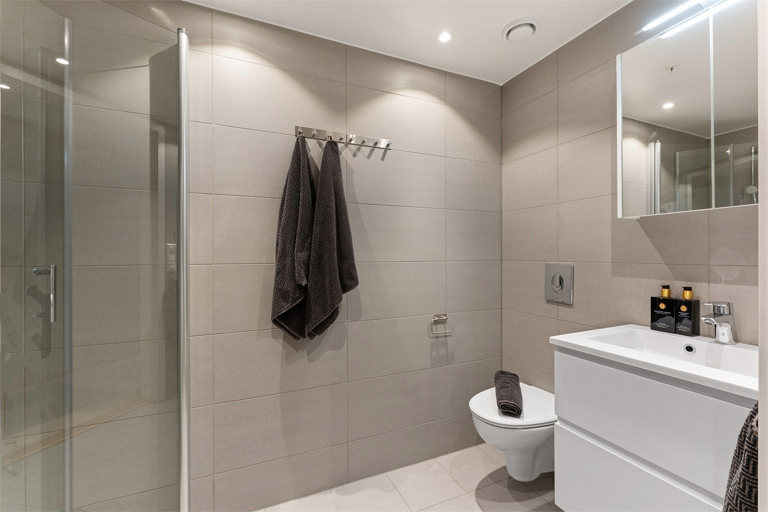 Delikat, flislagt bad fra 2023 med downlights i himling og gulvvarme.