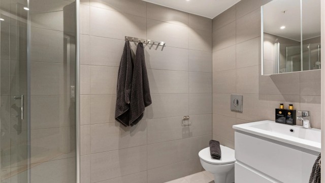 Delikat, flislagt bad fra 2023 med downlights i himling og gulvvarme.
