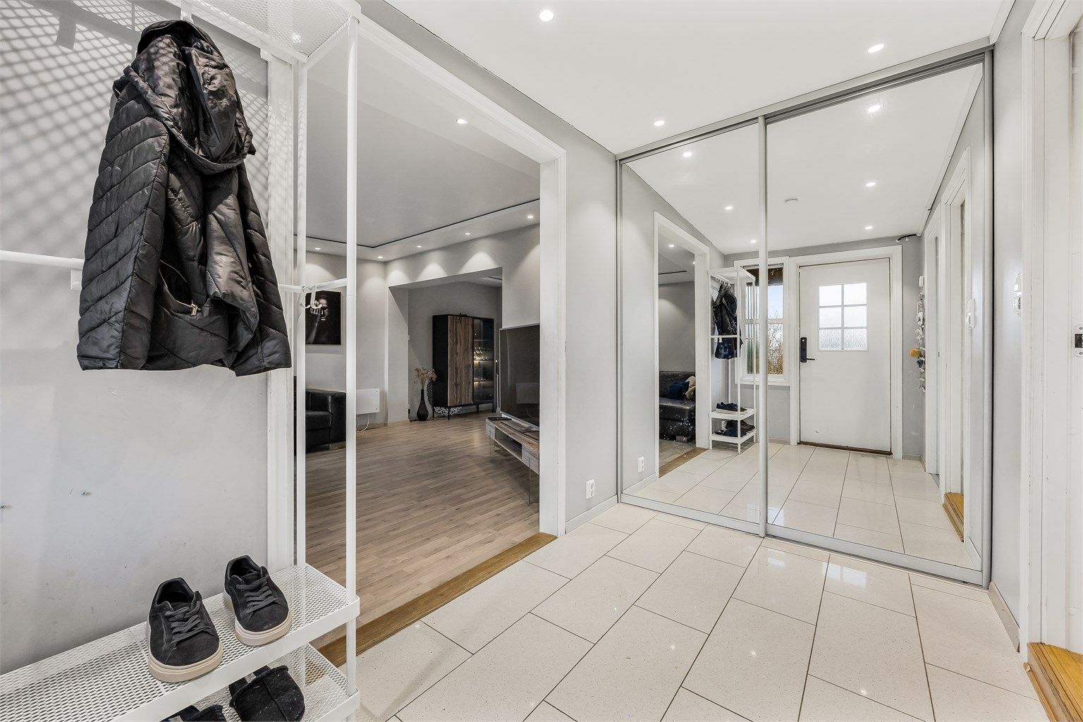 En romslig skyvedørsgarderobe med speilfronter gir rikelig med oppbevaringsplass for yttertøy og sko.