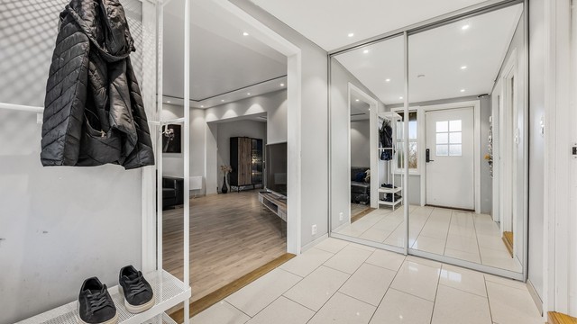 En romslig skyvedørsgarderobe med speilfronter gir rikelig med oppbevaringsplass for yttertøy og sko.
