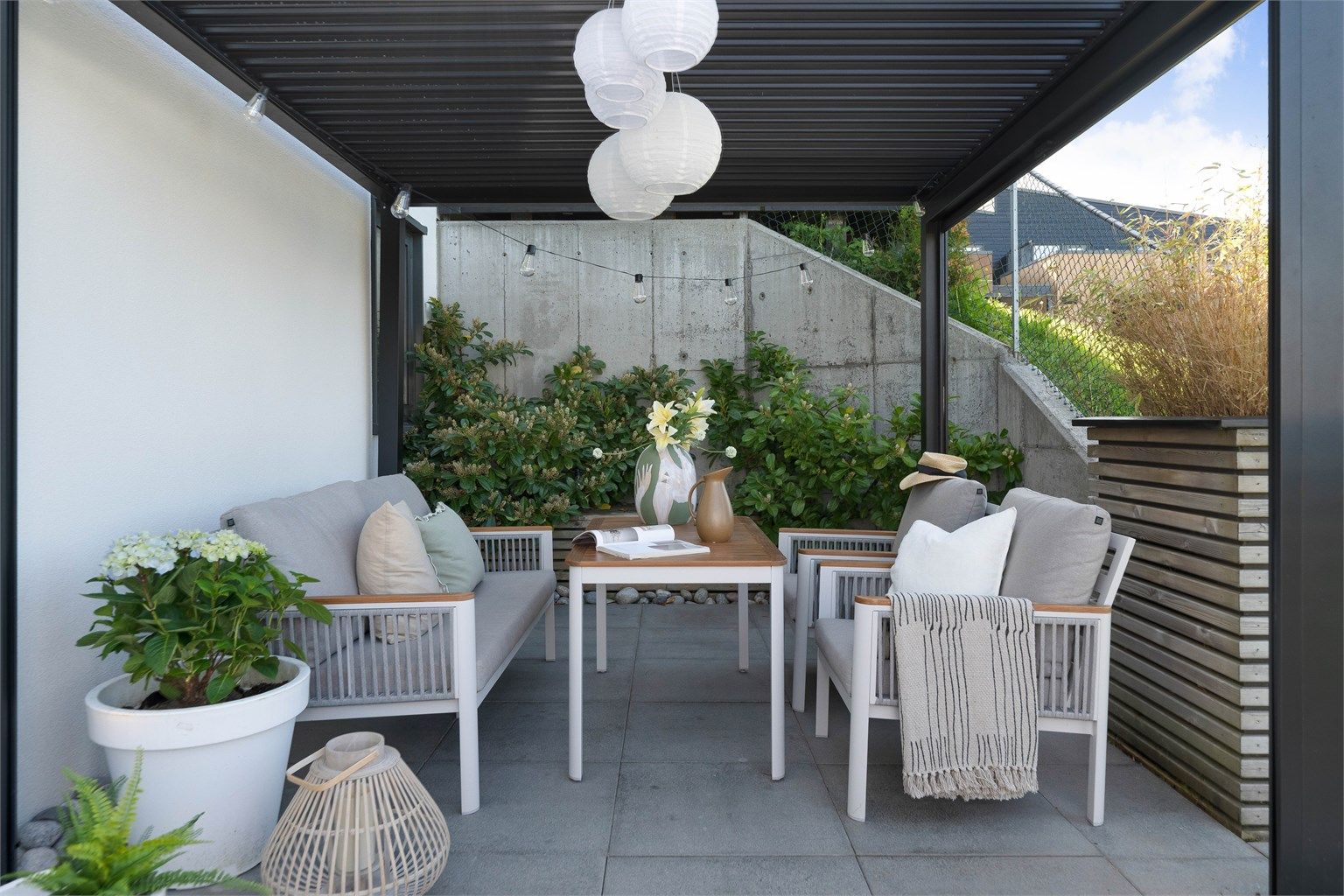 Nydelig uteplass på nedsiden av huset. Pent opparbeidet. De heller, pergola, blomsterkasser og terrassebord.