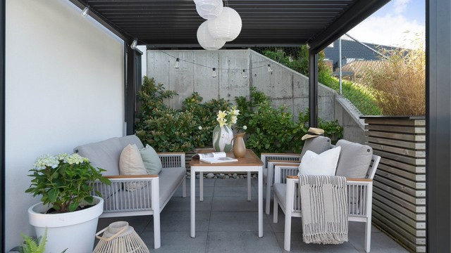 Nydelig uteplass på nedsiden av huset. Pent opparbeidet. De heller, pergola, blomsterkasser og terrassebord.