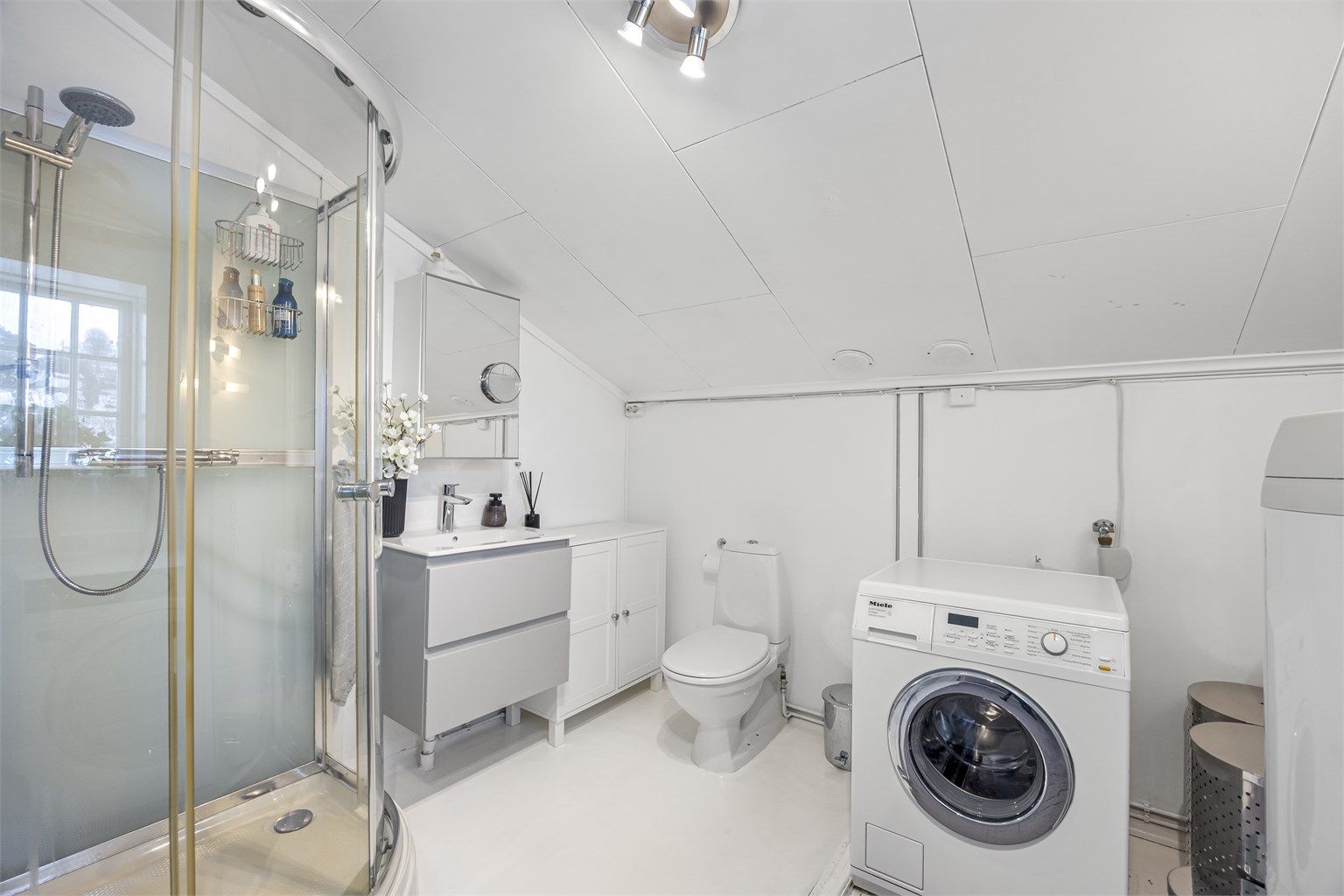 Badet i hyblen er utstyrt med dusjkabinett, toalett og servantinnredning. Det er varmekabler i deler av gulvet.