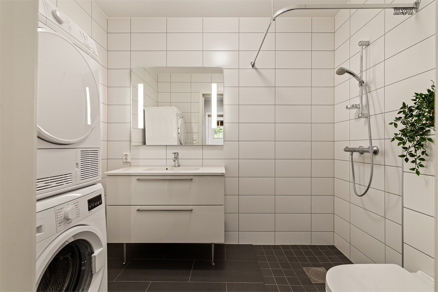 Kombinert bad og vaskerom i underetasjen med opplegg for vaskemaskin og tørketrommel.