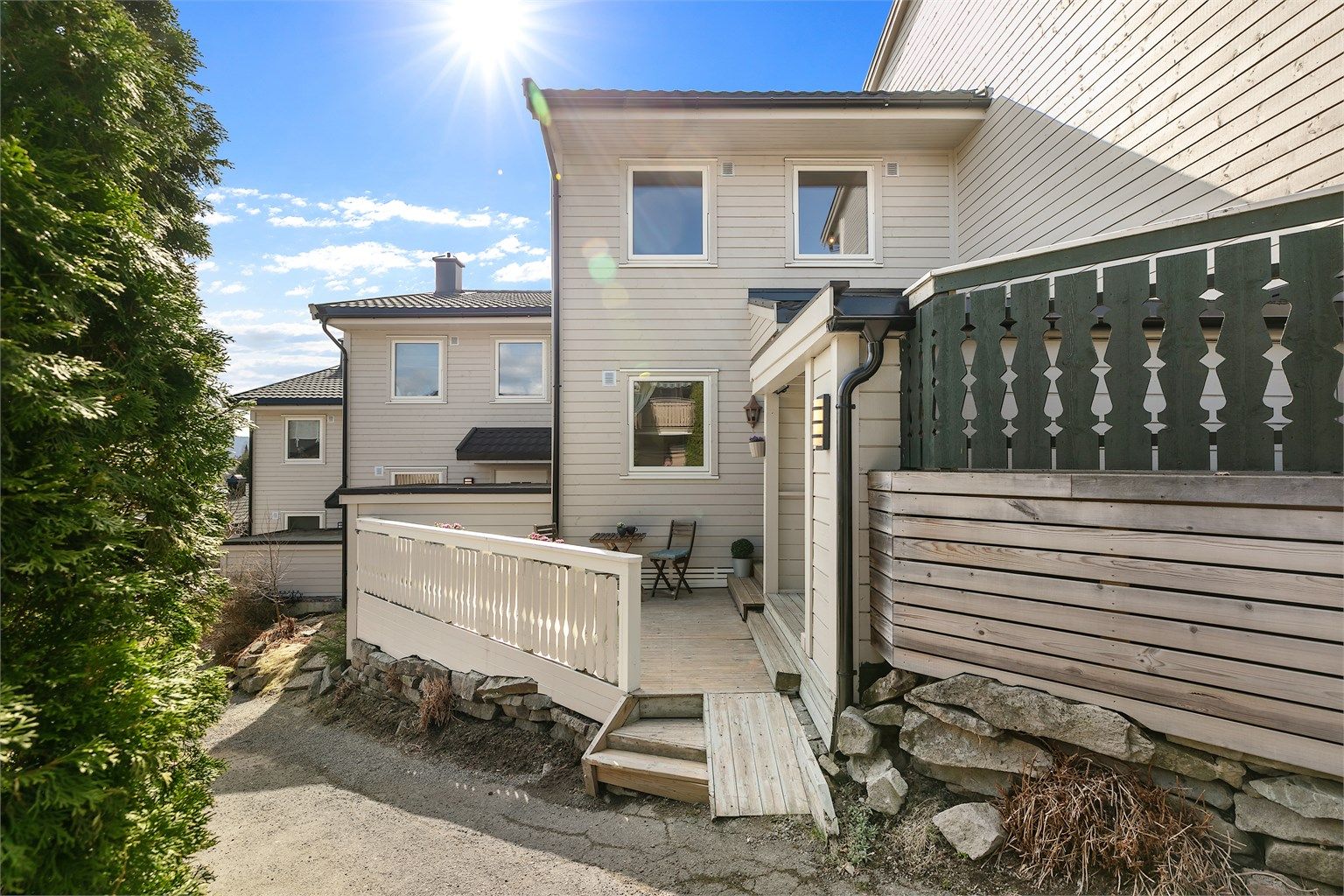 Fasade, stor terrasse laget i front av boligen med sitteplass og bod.