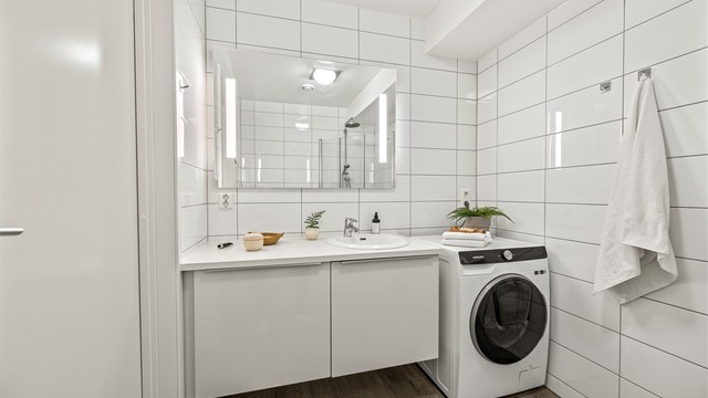 Badet i første etasje har opplegg for vaskemaskin, dusjhjørne med glassdører og vegghengt toalett.