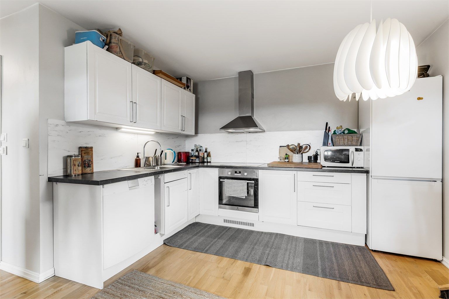 Hybel: Åpen kjøkkenløsning. Innredning fra byggeår. Profilerte fronter. Benkeplate med laminert overflate. Nedfelt kjøkkenvask med armatur. Benkeskapsbelysning og stikkontakter over kjøkkenbenk. Integrert stekeovn og platetopp.