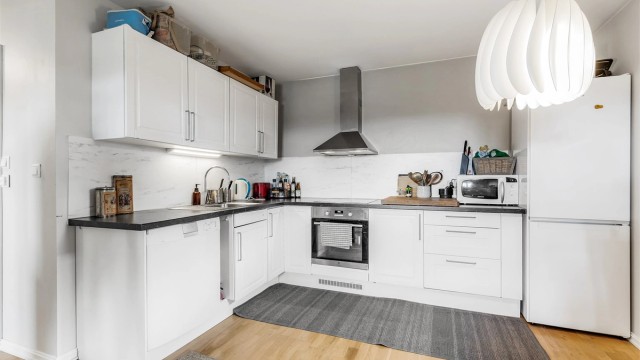 Hybel: Åpen kjøkkenløsning. Innredning fra byggeår. Profilerte fronter. Benkeplate med laminert overflate. Nedfelt kjøkkenvask med armatur. Benkeskapsbelysning og stikkontakter over kjøkkenbenk. Integrert stekeovn og platetopp.