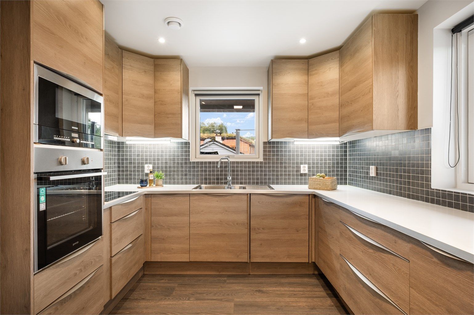 Lekkert kjøkken med integrerte hvitevarer som platetopp, stekeovn, mikro, oppvaskmaskin og kjøleskap m/ frys. 