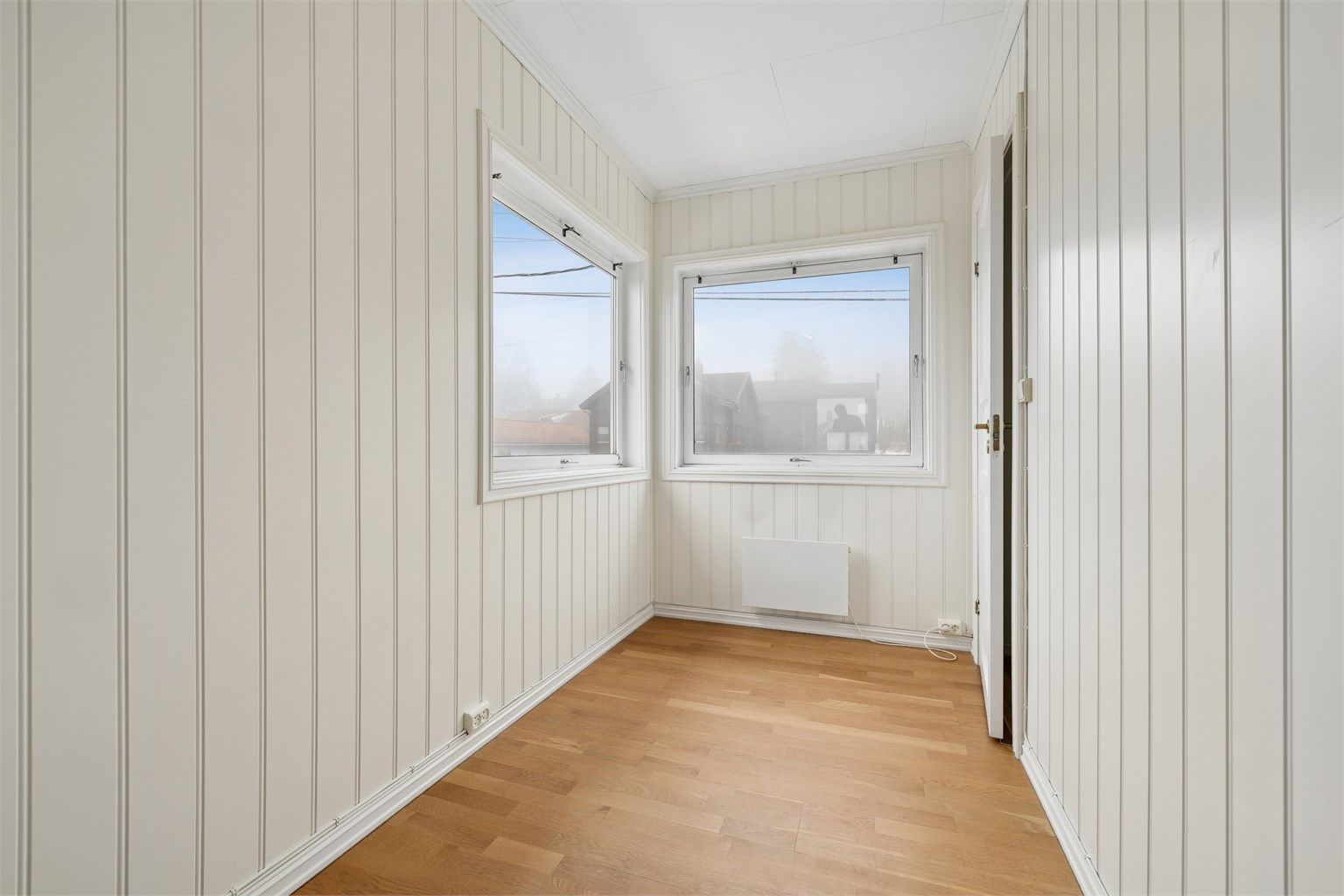 Soverom med malte panelplater og plass til seng og oppbevaring.