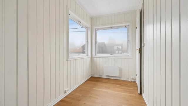 Soverom med malte panelplater og plass til seng og oppbevaring.