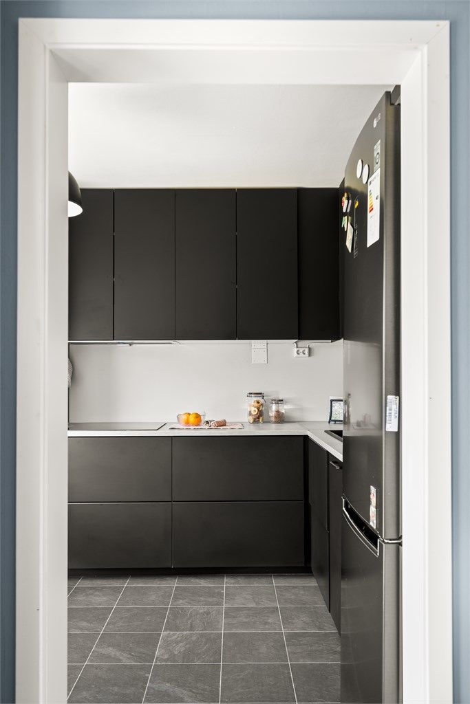 Separat kjøkken med moderne innredning med slette, mørke fronter og laminat på gulv.