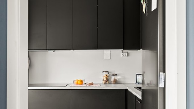 Separat kjøkken med moderne innredning med slette, mørke fronter og laminat på gulv.