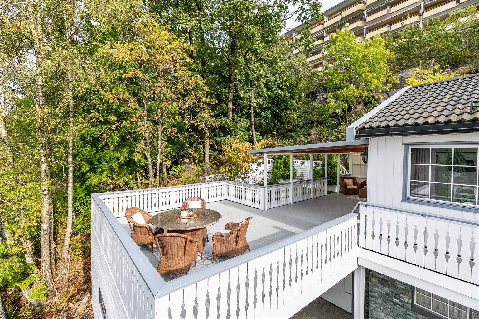 Sommerstid omfavnes boligen av velvoksne løvtrær som er naturlig skjermende. Bildet er tatt i 2025.