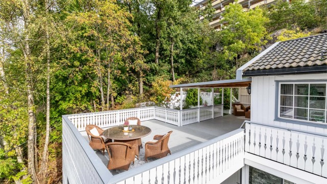 Sommerstid omfavnes boligen av velvoksne løvtrær som er naturlig skjermende. Bildet er tatt i 2025.