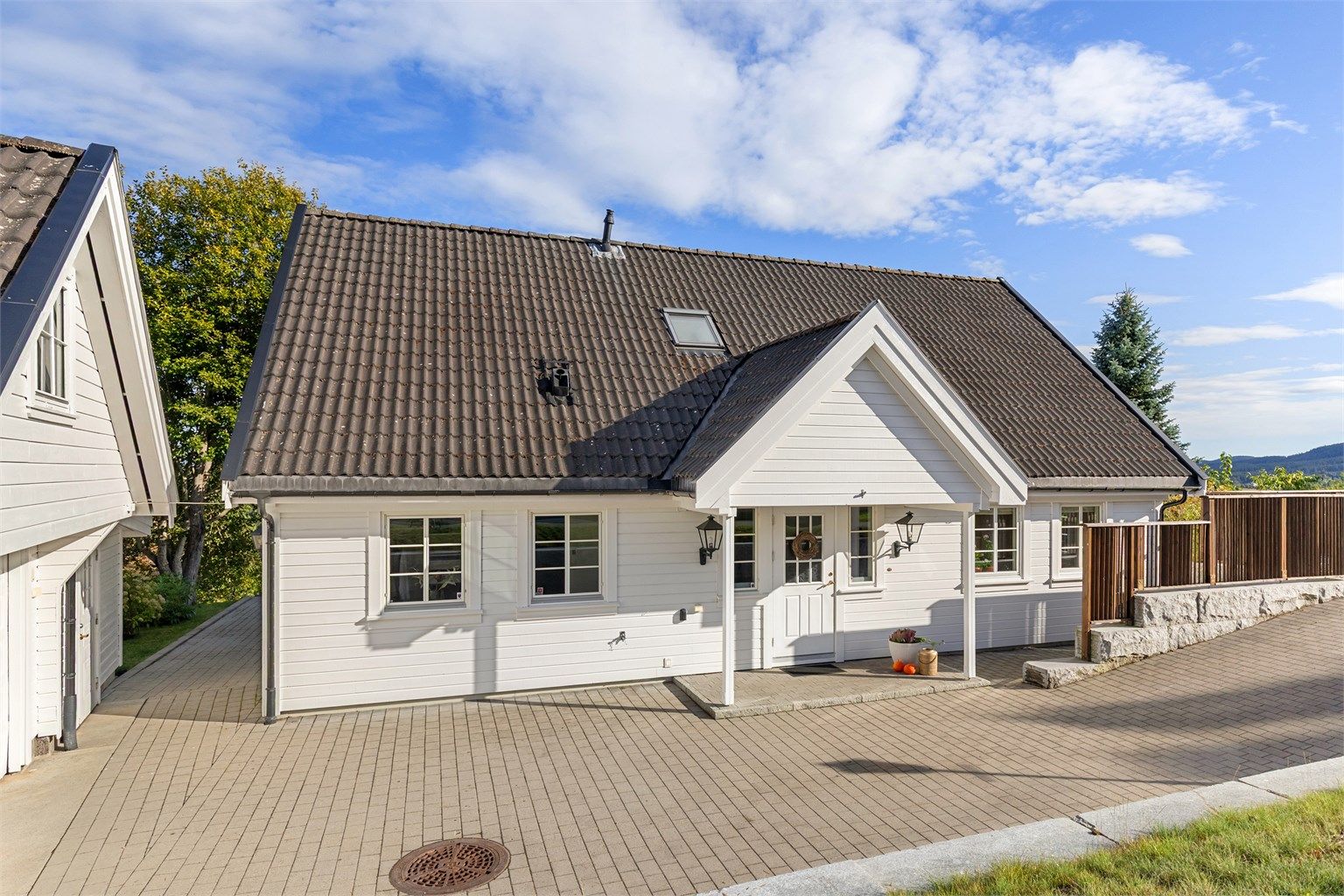Overbygget inngangsparti med belegningsstein på gårdsplassen og adkomst til boligen.