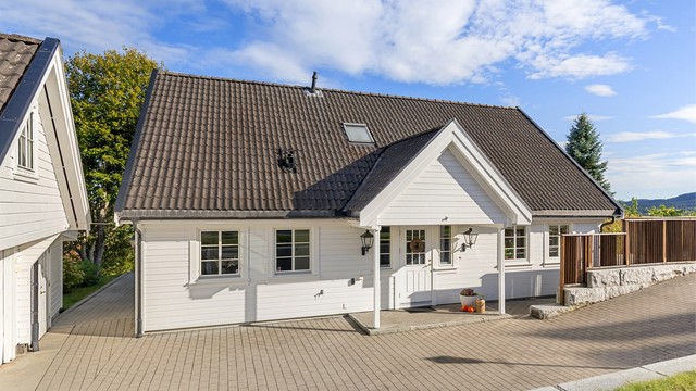 Overbygget inngangsparti med belegningsstein på gårdsplassen og adkomst til boligen.