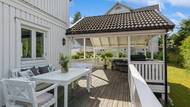 En romslig, overbygd del av terrassen gir en komfortabel og værbeskyttet oppholdssone. Dette blir en naturlig forlengelse av stuen og et perfekt sted for både avslapning og hyggelige sammenkomster gjennom store deler av året.