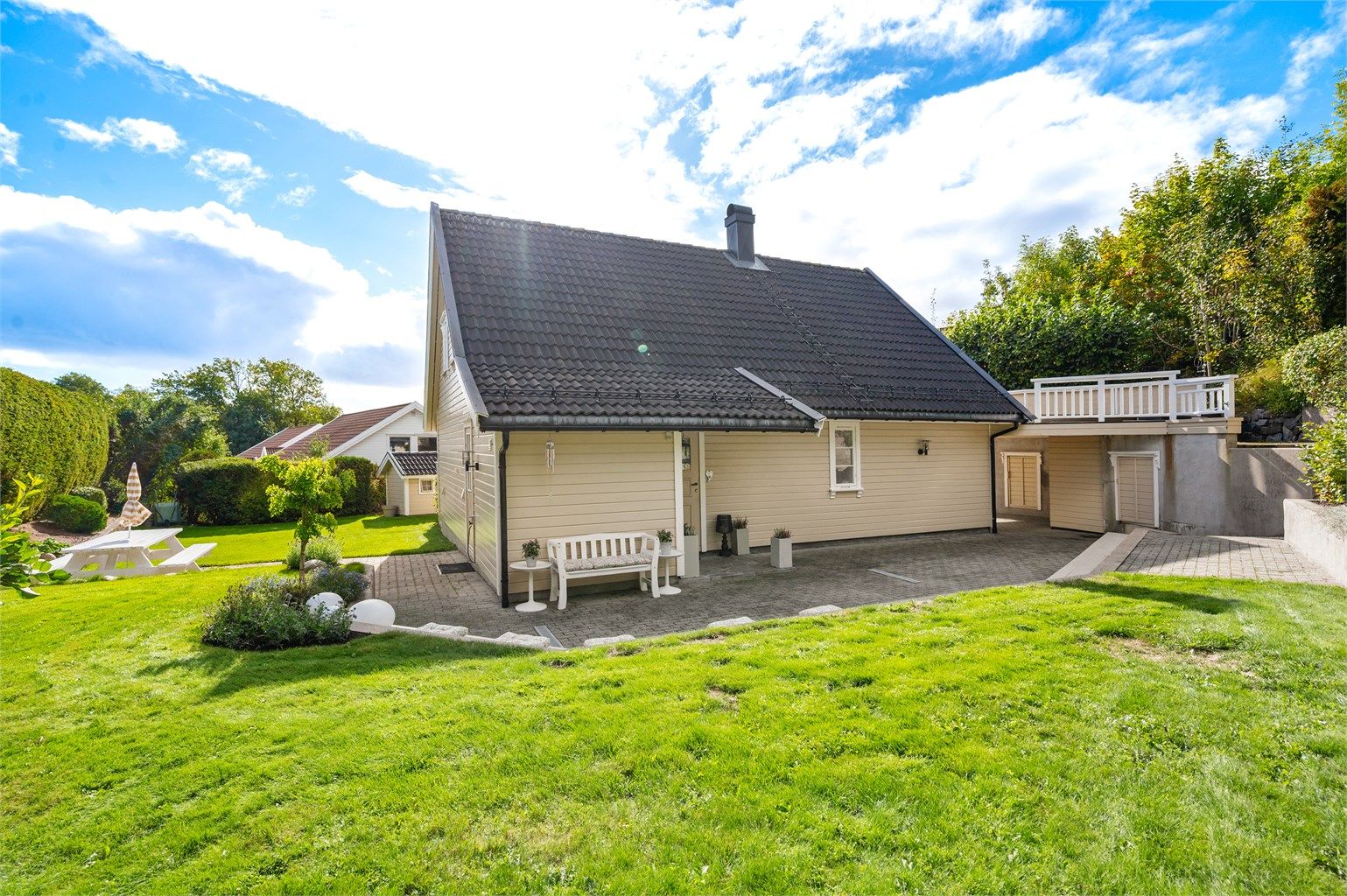 Tomten er tilnærmet flat og pent opparbeidet med plenarealer, beplantning og belegningsstein.