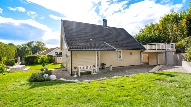 Tomten er tilnærmet flat og pent opparbeidet med plenarealer, beplantning og belegningsstein.