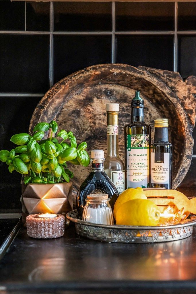 Mørke flislagte veggflater over kjøkkenbenken med benkeskapsbelysning.