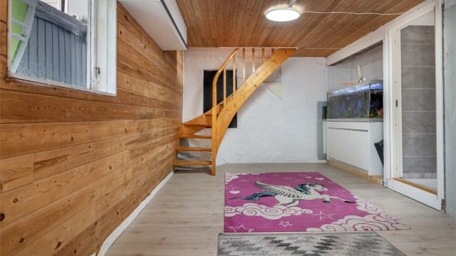 Kjellerstue med lakkert trapp og vegger med panel.