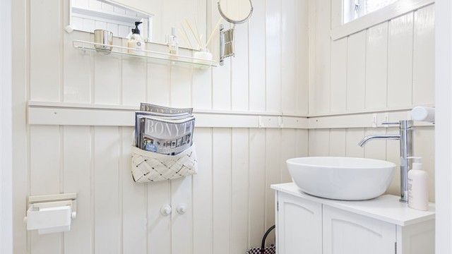 Praktisk toalettrom i hovedetasjen med flislagt gulv og nyere servantinnredning.