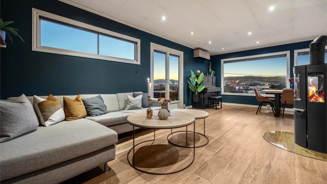 Stuen er et lunt samlingspunkt med peis (pipe bør rehabiliteres), parkett på gulv og store vindusflater.