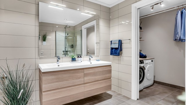 Badet har dusjhjørne med innfellbare glassdører og praktisk vaskeromsnisje.