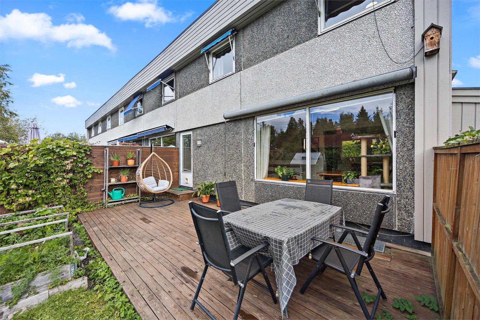 Vestvendt terrasse med tredekke, levegg og markise over stuevinduet.