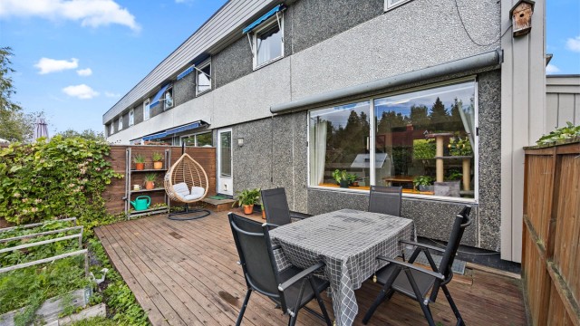 Vestvendt terrasse med tredekke, levegg og markise over stuevinduet.