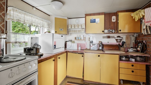 Kjøkkeninnredningen har glatte fronter fra ukjent årstall og benkeplate med laminert overflate.