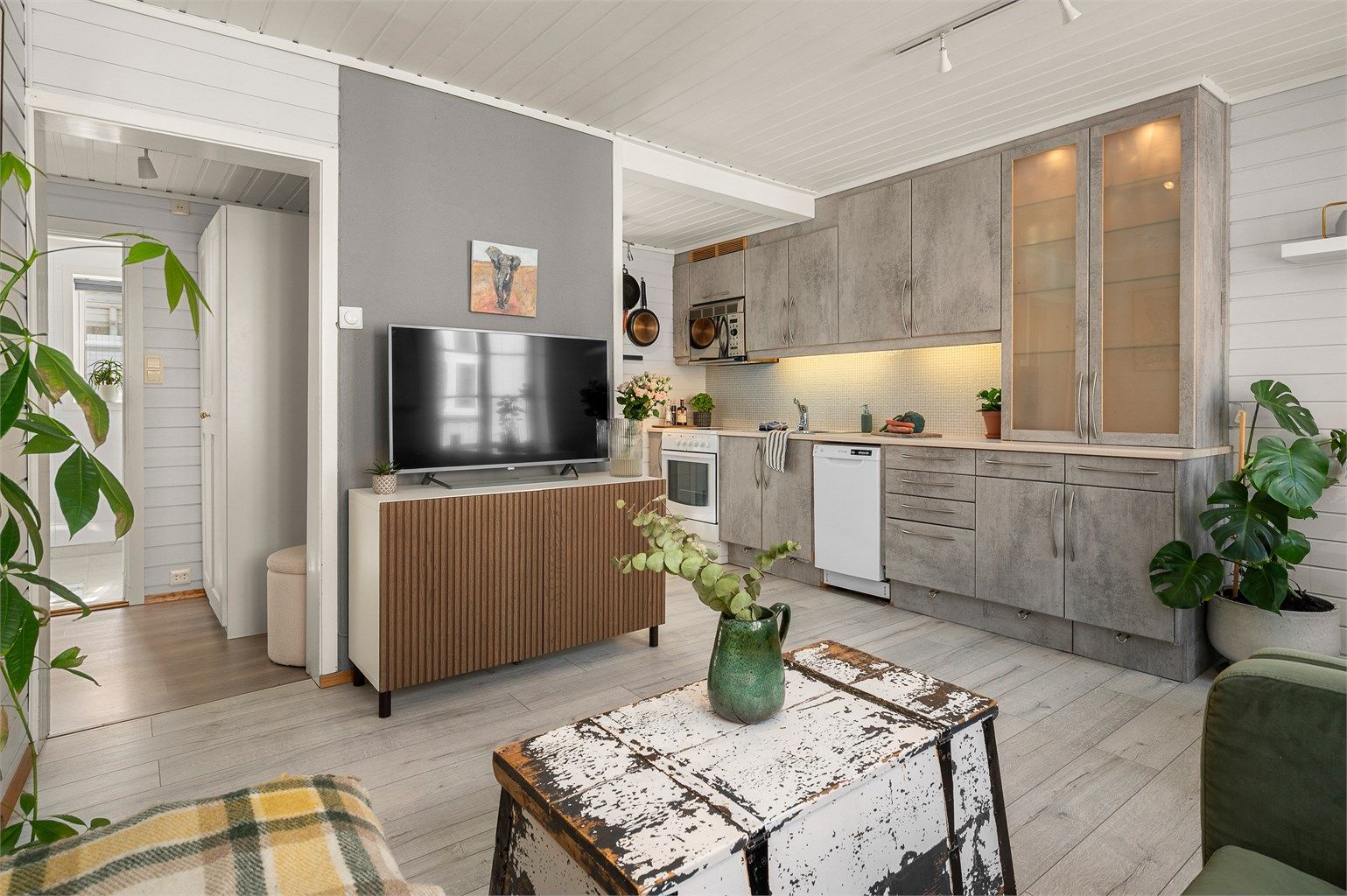 Kjøkkenet ligger naturlig tilbaketrukket fra stuen og er innredet med lyse slette flater, benkeplate av laminat og fliser mellom kjøkkenbenk og overskap.