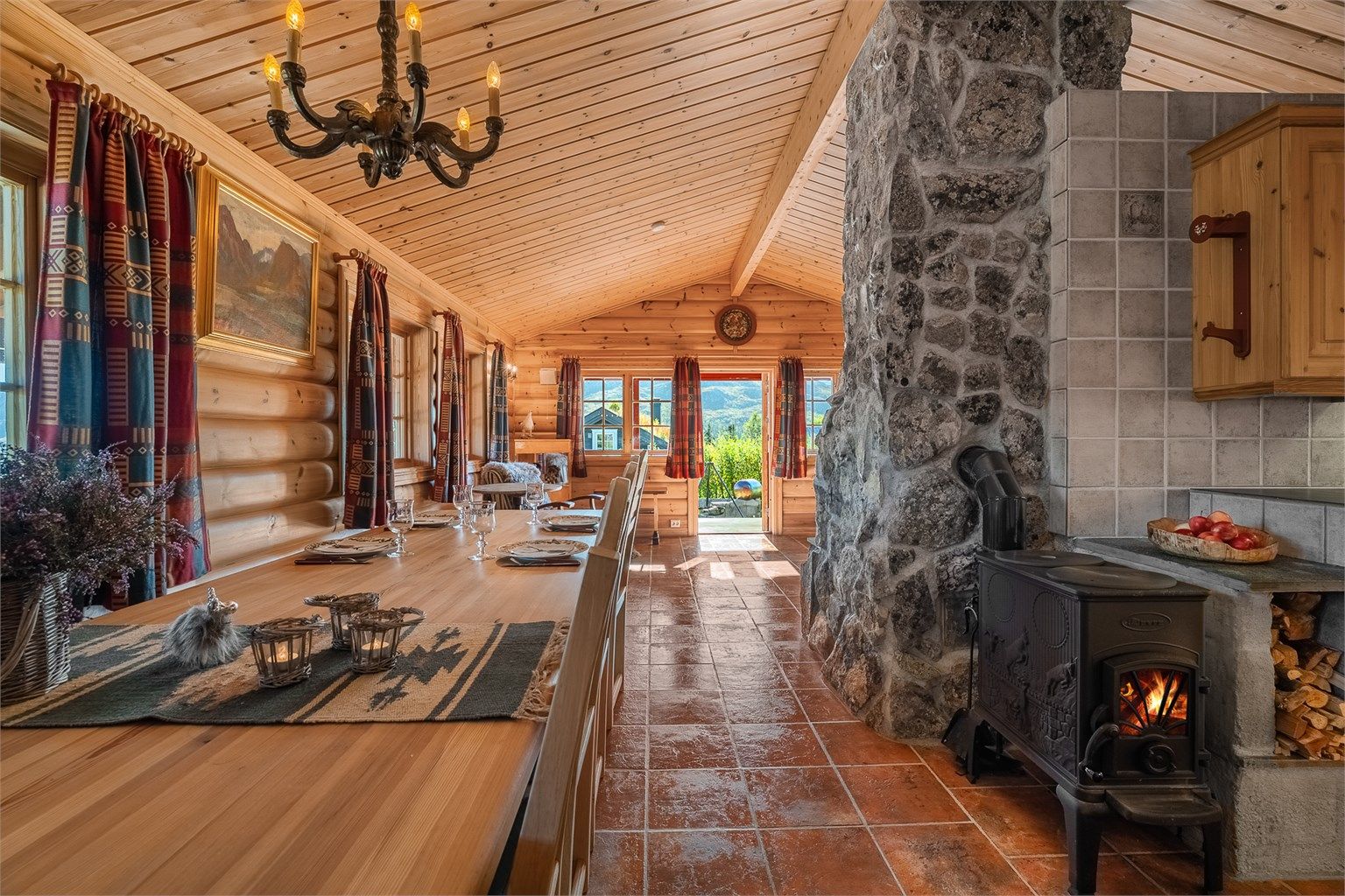 Spisestuen har plass til langbord for mange gjester, plassert lunt ved peis og vedovn.