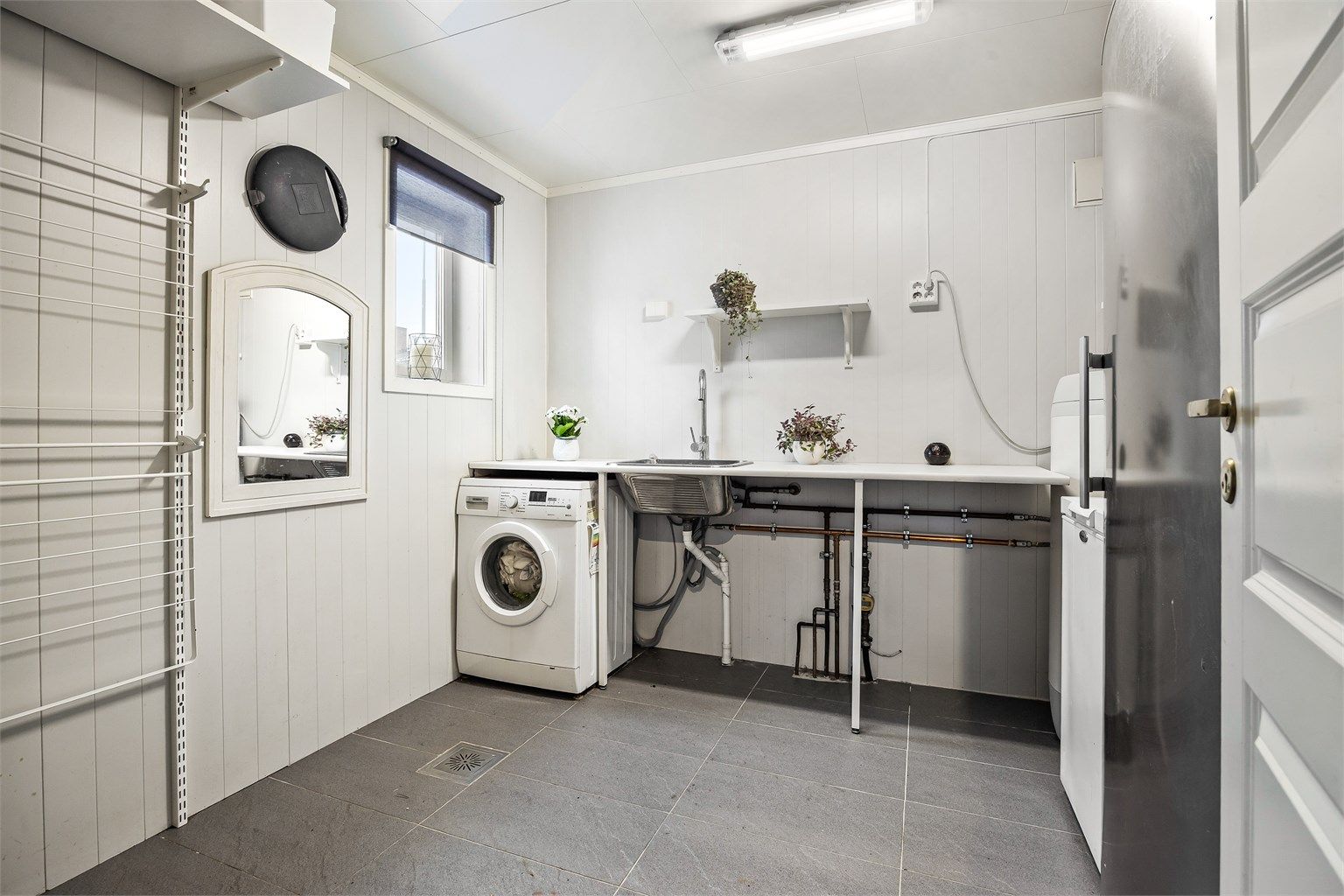 Separat vaskerom med utslagsvask i benk og opplegg for vaskemaskin - Del av rommet er opprinnelig en bod.