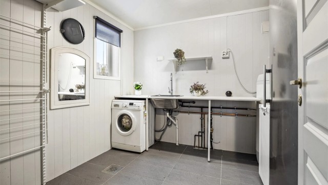 Separat vaskerom med utslagsvask i benk og opplegg for vaskemaskin - Del av rommet er opprinnelig en bod.