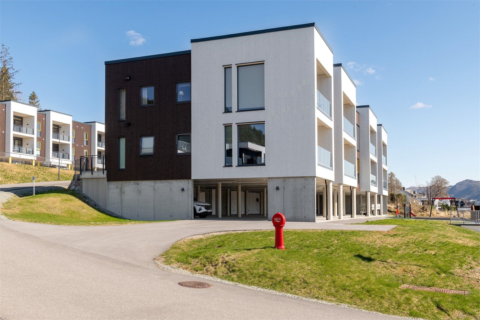 Bygget har en moderne fasade med en kombinasjon av stående trekledning og fasadeplater