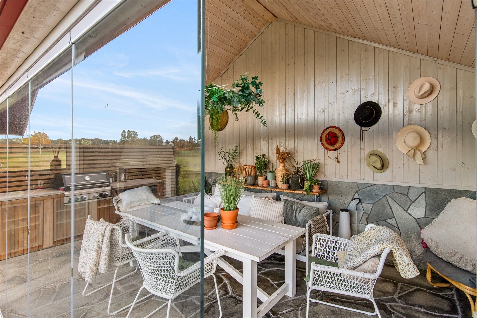 Inne i den 22 m² store hagestuen er det en lun og innbydende atmosfære, med glassvegger som kan skyves helt til side.