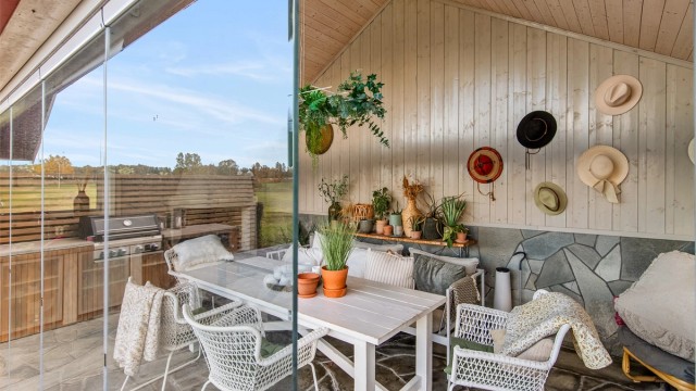 Inne i den 22 m² store hagestuen er det en lun og innbydende atmosfære, med glassvegger som kan skyves helt til side.